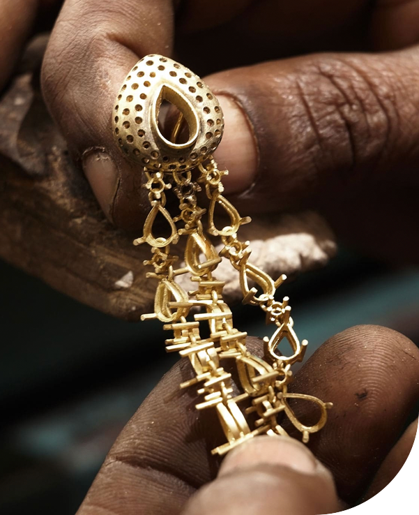 Artisan tenant une boucle d’oreille pendante en or jaune