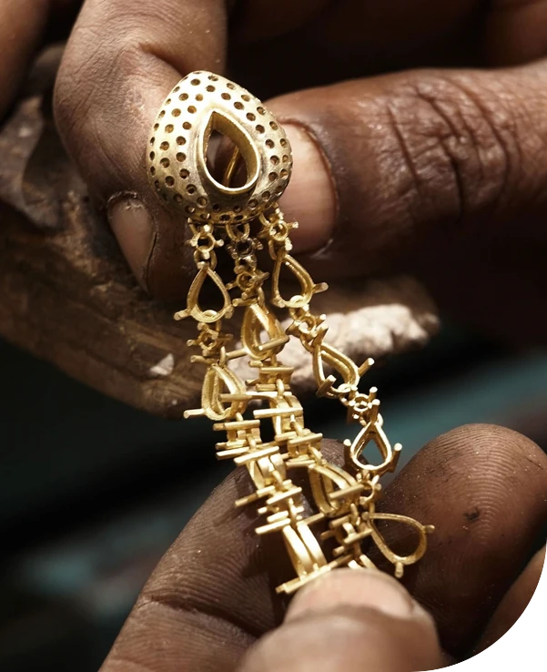 Artisan tenant une boucle d’oreille pendante en or jaune